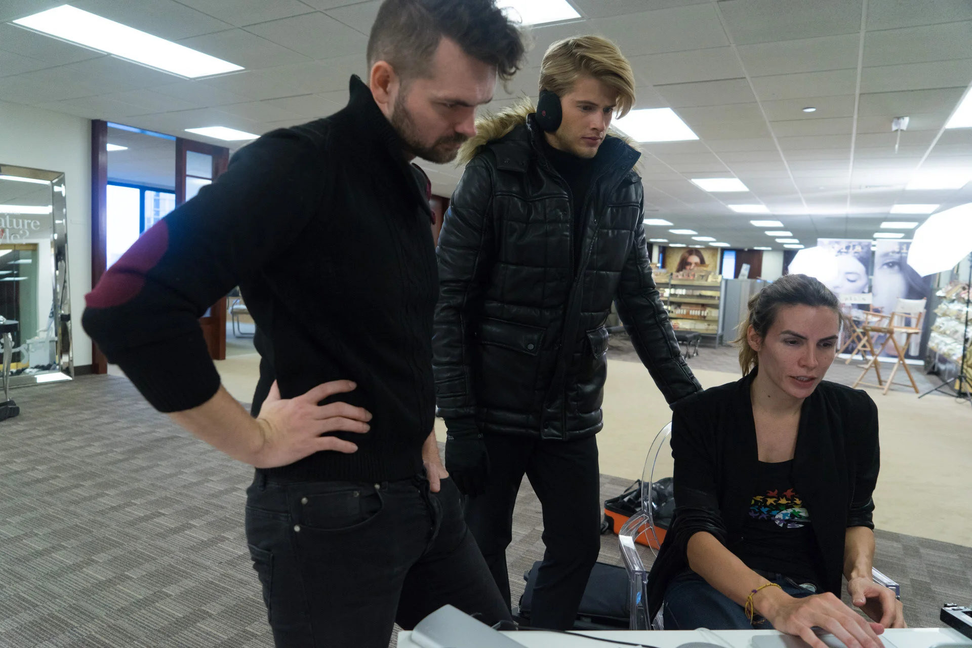Three people reviewing a computer together in a bright studio workspace.