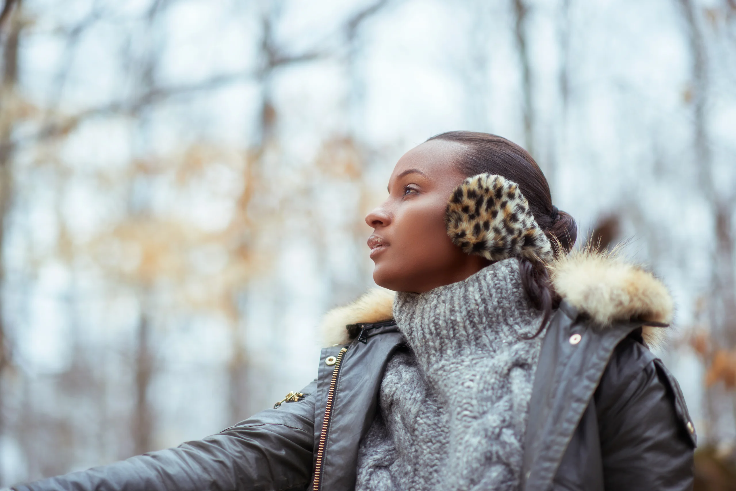 A model in leopard-print earmuffs, a gray cable-knit sweater and a fur-trimmed coat.