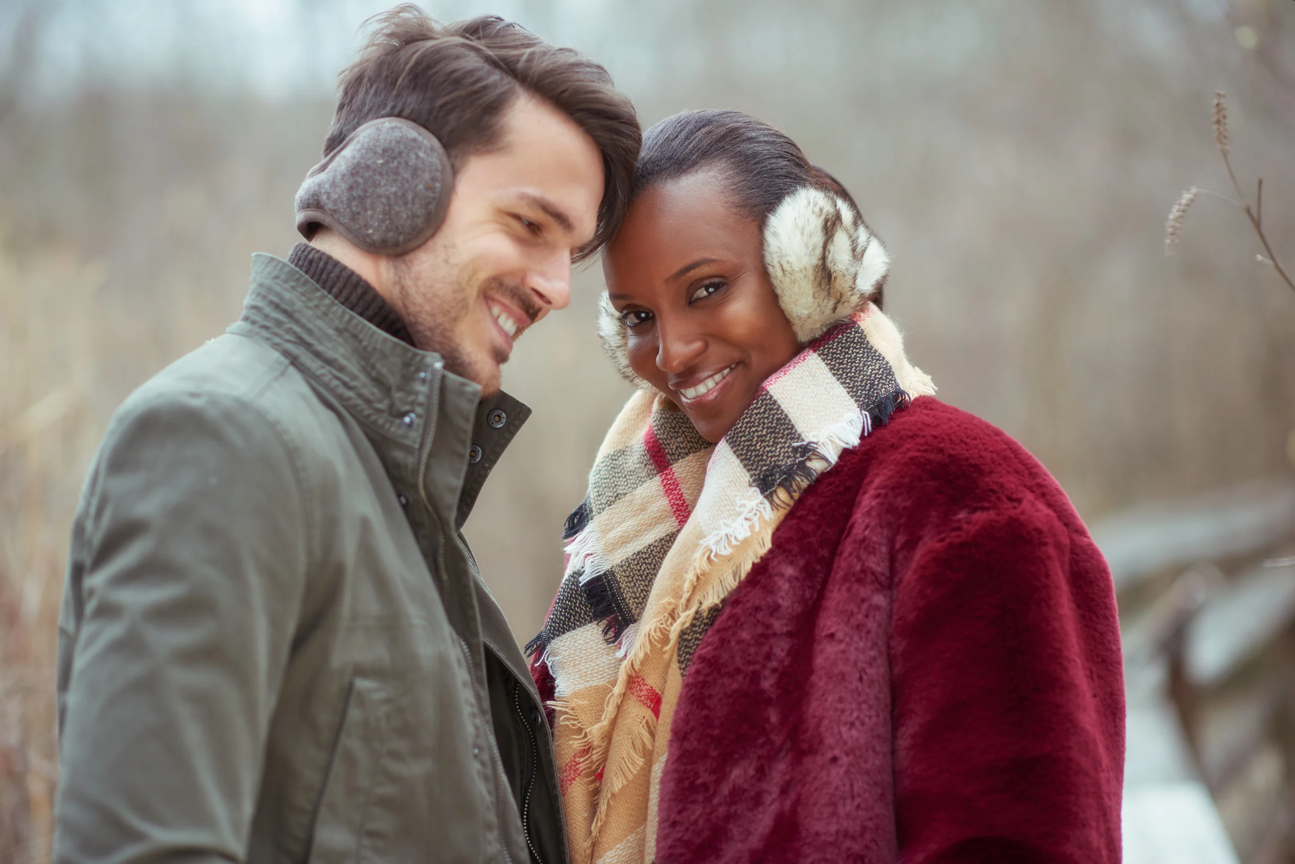 Two smiling models leaning their heads together while wearing patterned earmuffs.