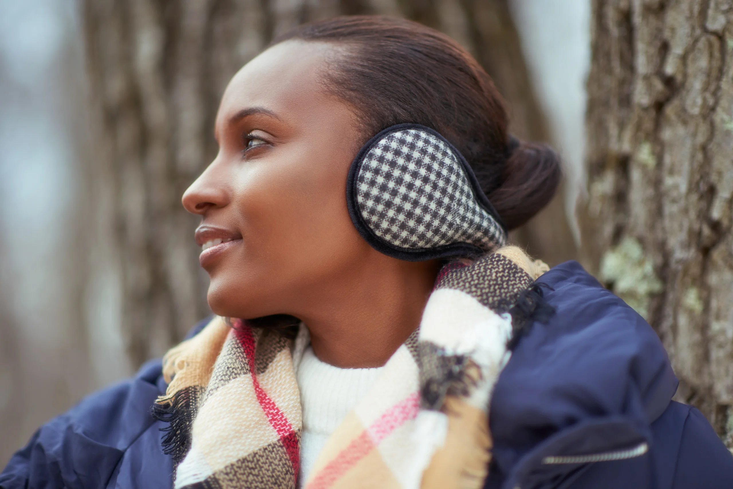 A model in checked earmuffs and a multicolored scarf looking to the side.