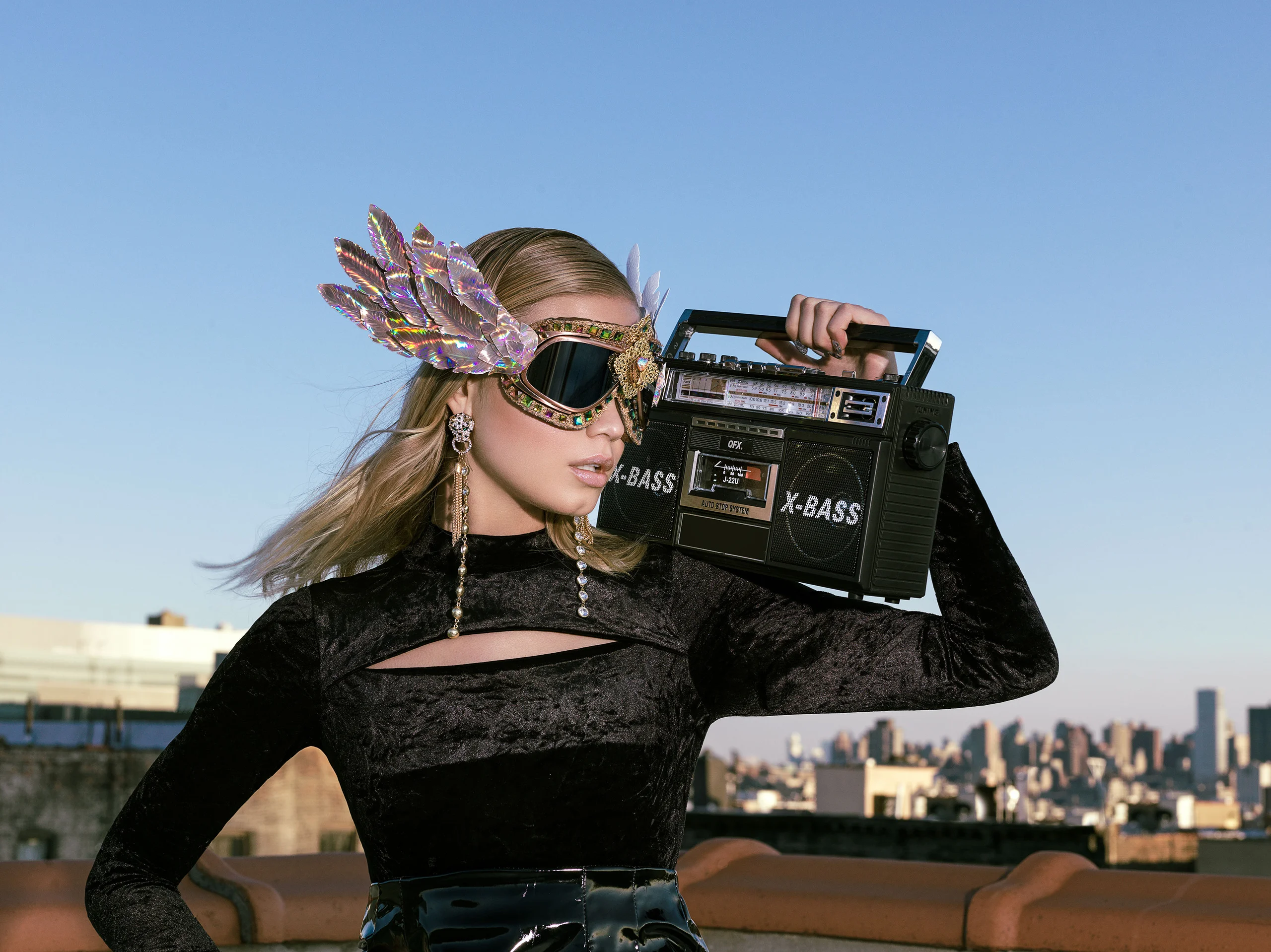 A model wearing goggles and holding a portable radio on a rooftop.