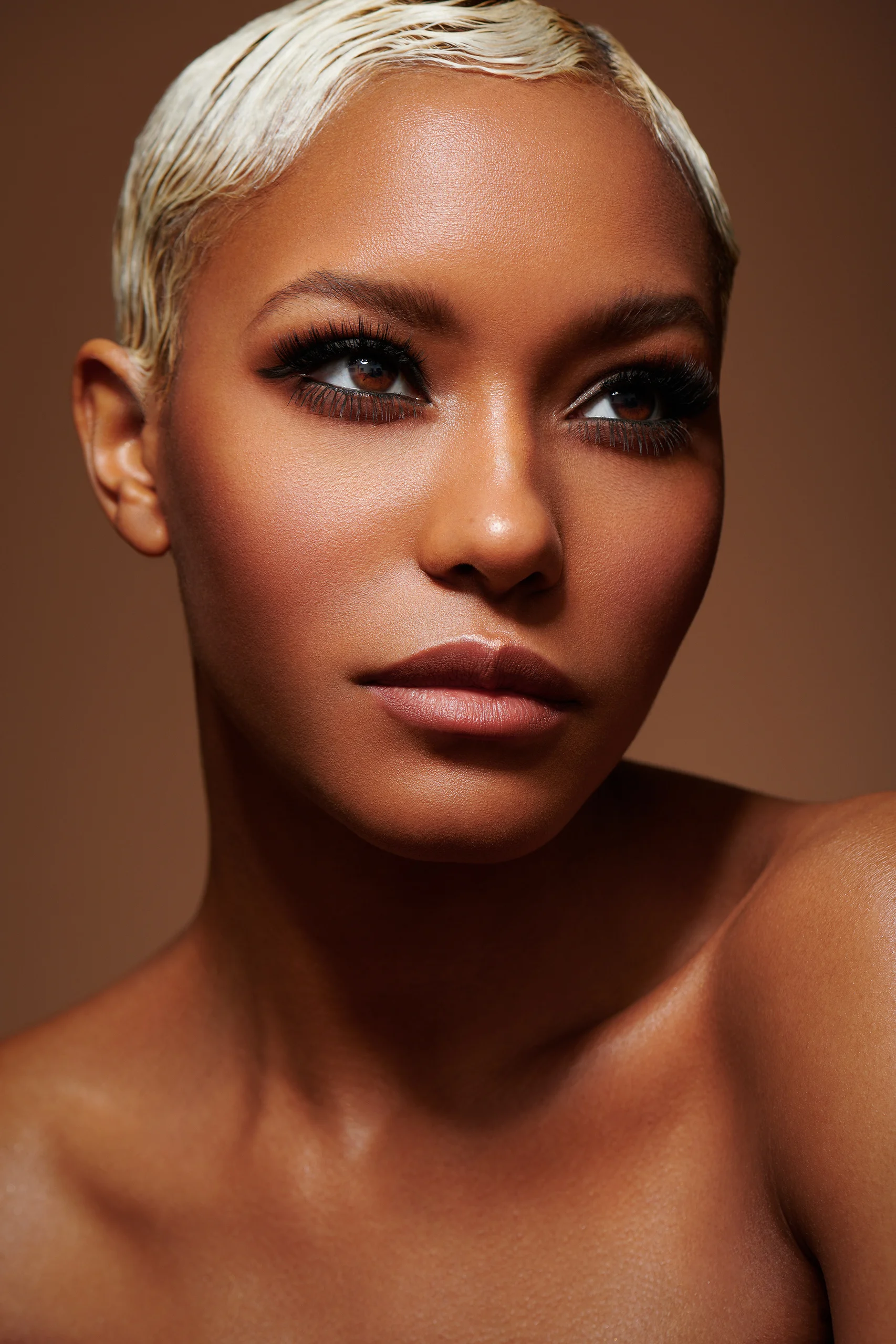 A close beauty portrait with dramatic eyeliner and a warm shadowed background.