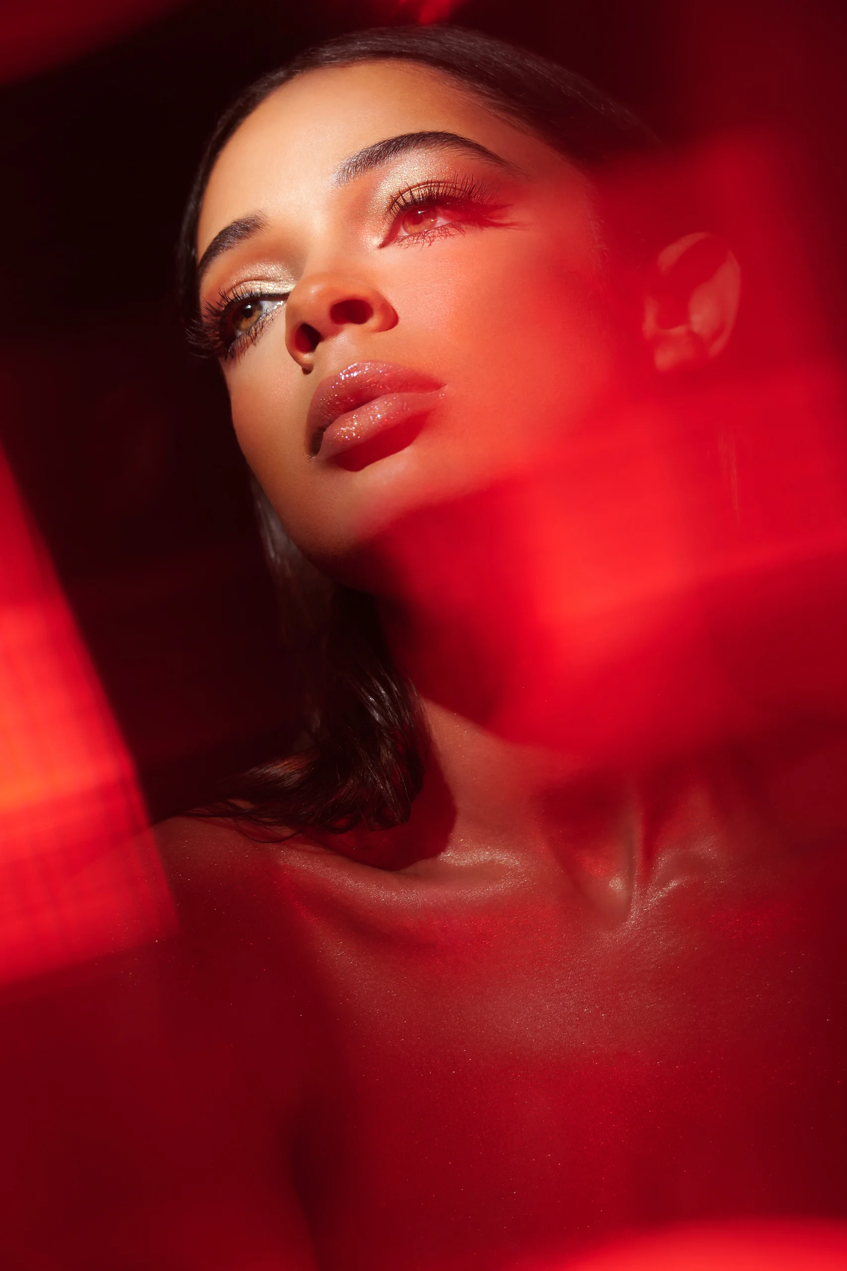A beauty portrait looking upward through bright red reflected light.