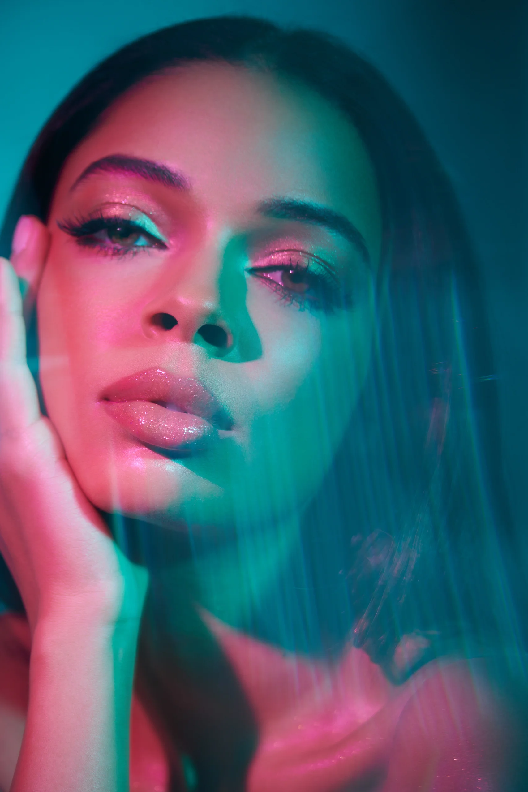 A beauty portrait with pink and turquoise light and soft reflections.