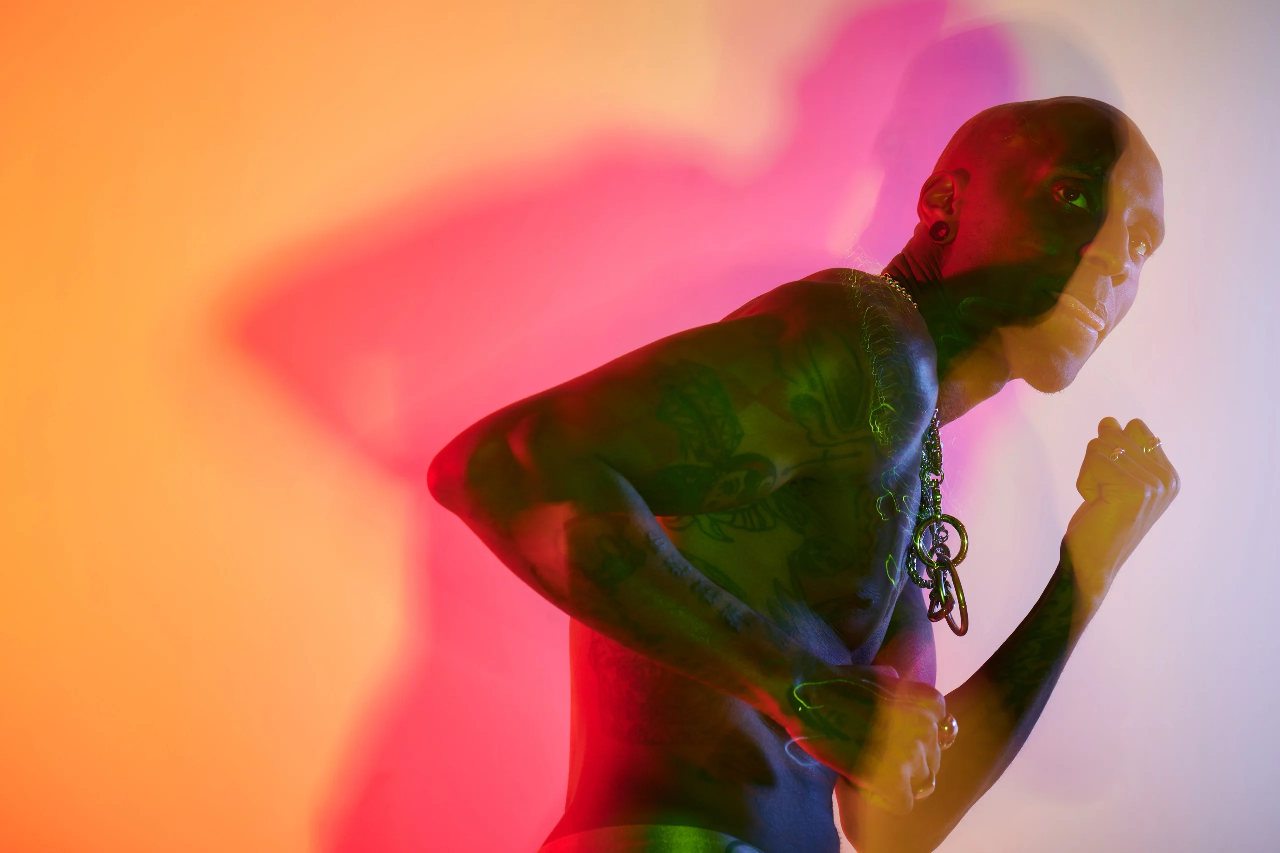 A figure in profile with one fist raised, surrounded by orange light and a broad pink shadow.