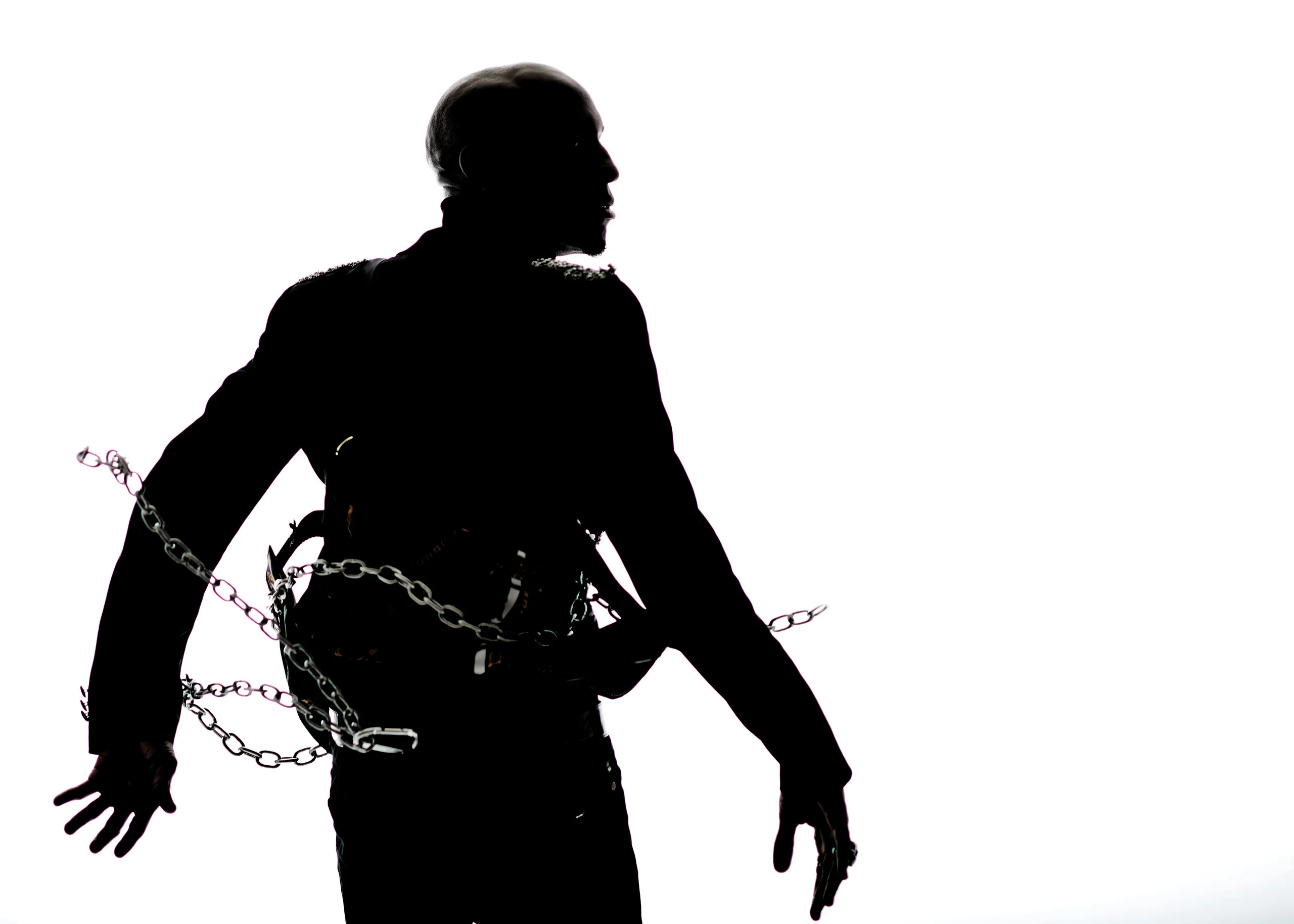 A dark silhouette with outstretched arms and a chain around the waist against white.