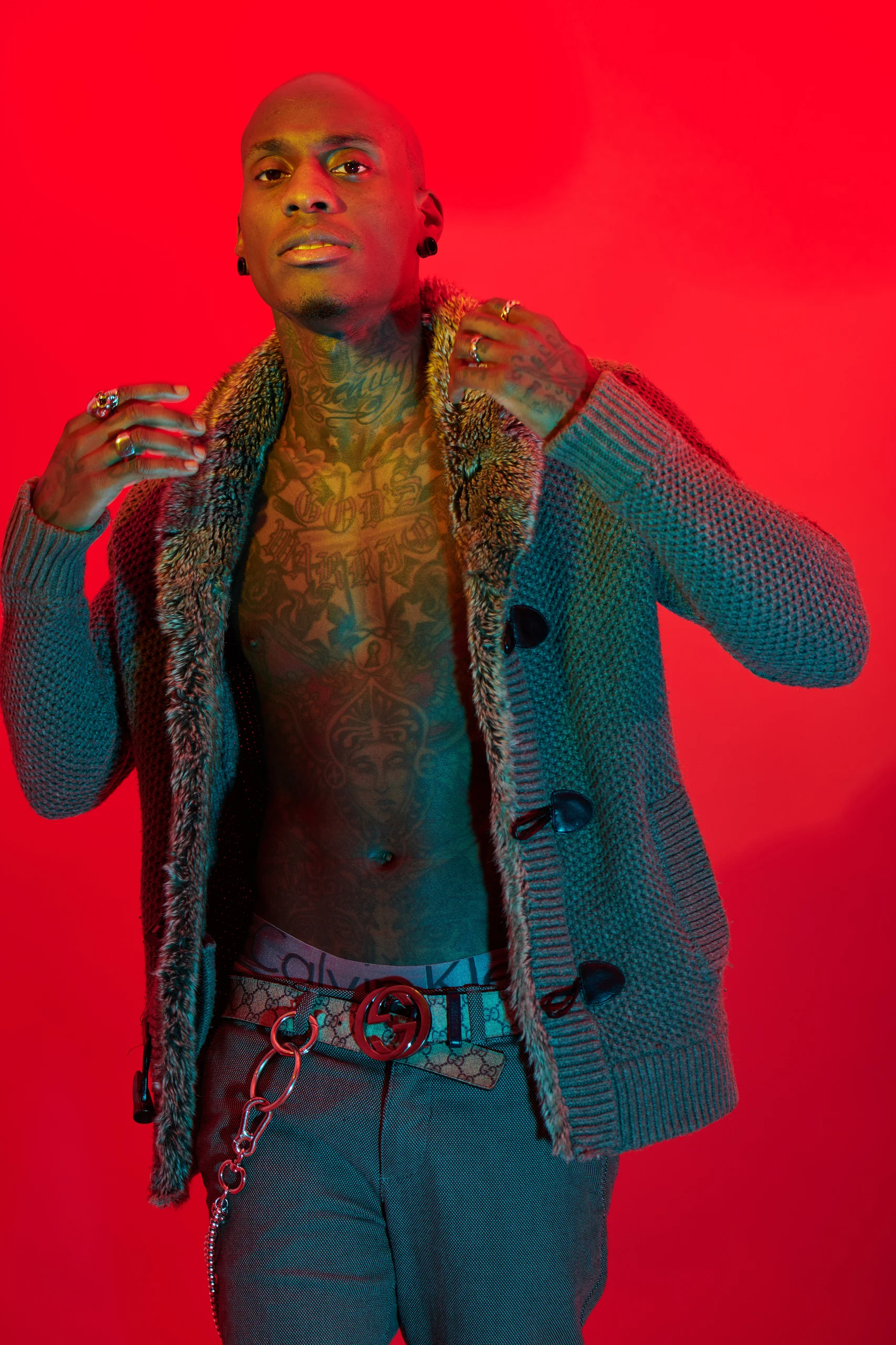 A model holding the edges of an open coat under green and red light.