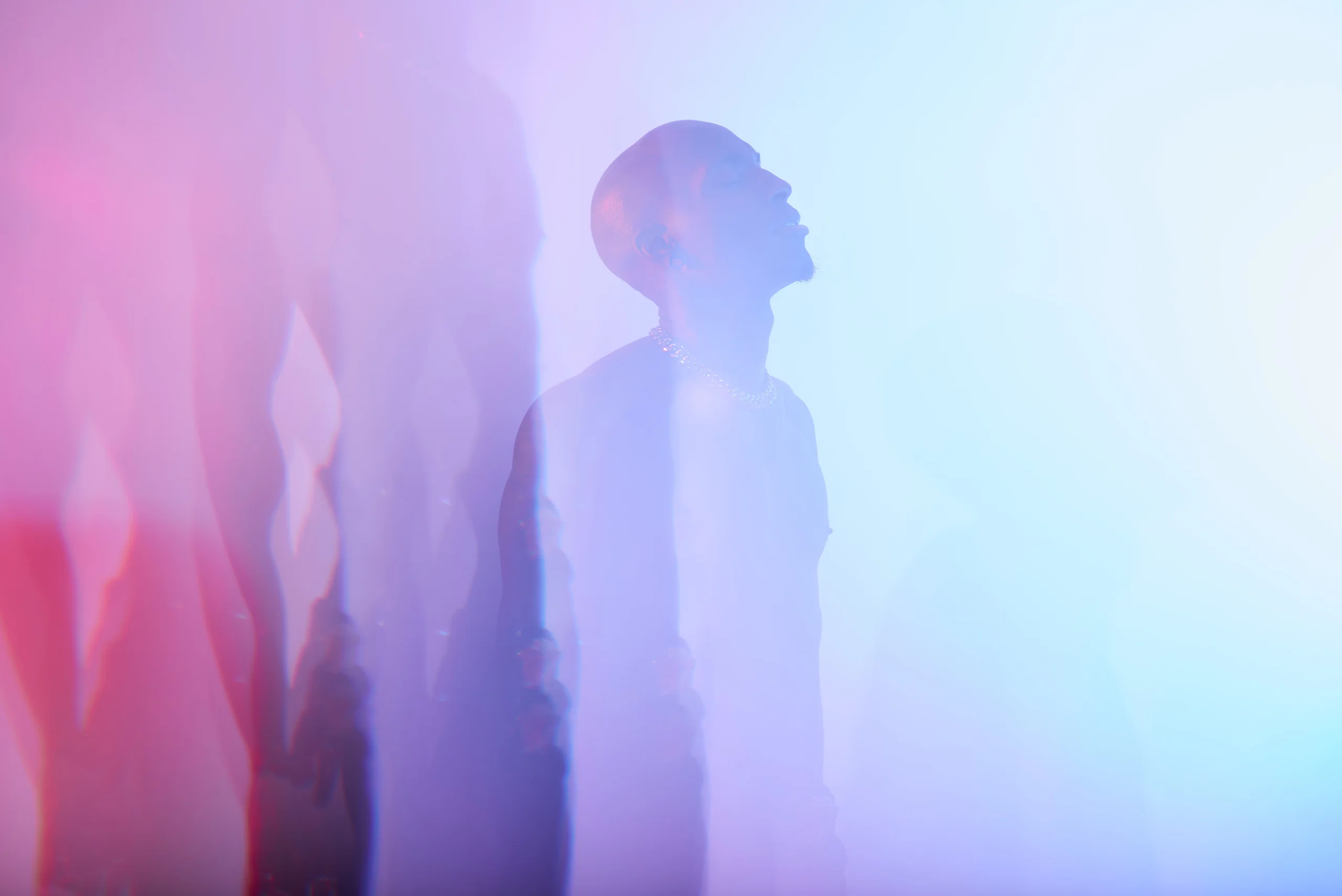 A profile silhouette repeated across pale pink and blue light.