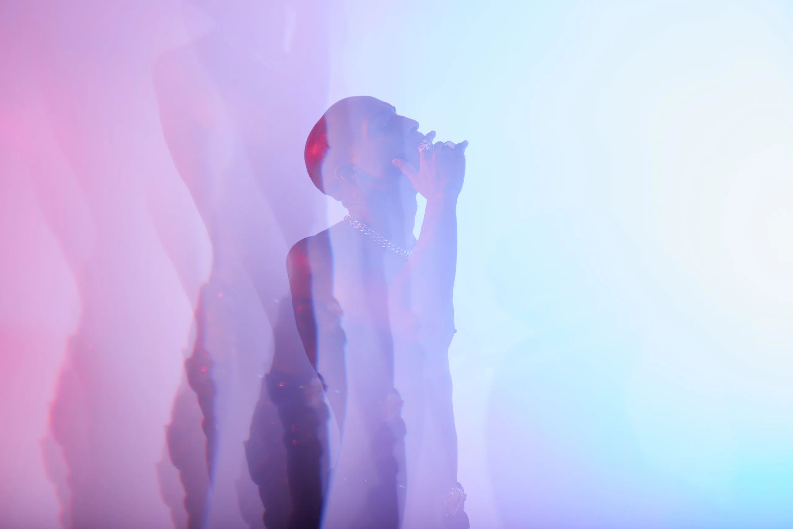 A figure leaning back with a hand near the face, echoed in pink and blue silhouettes.