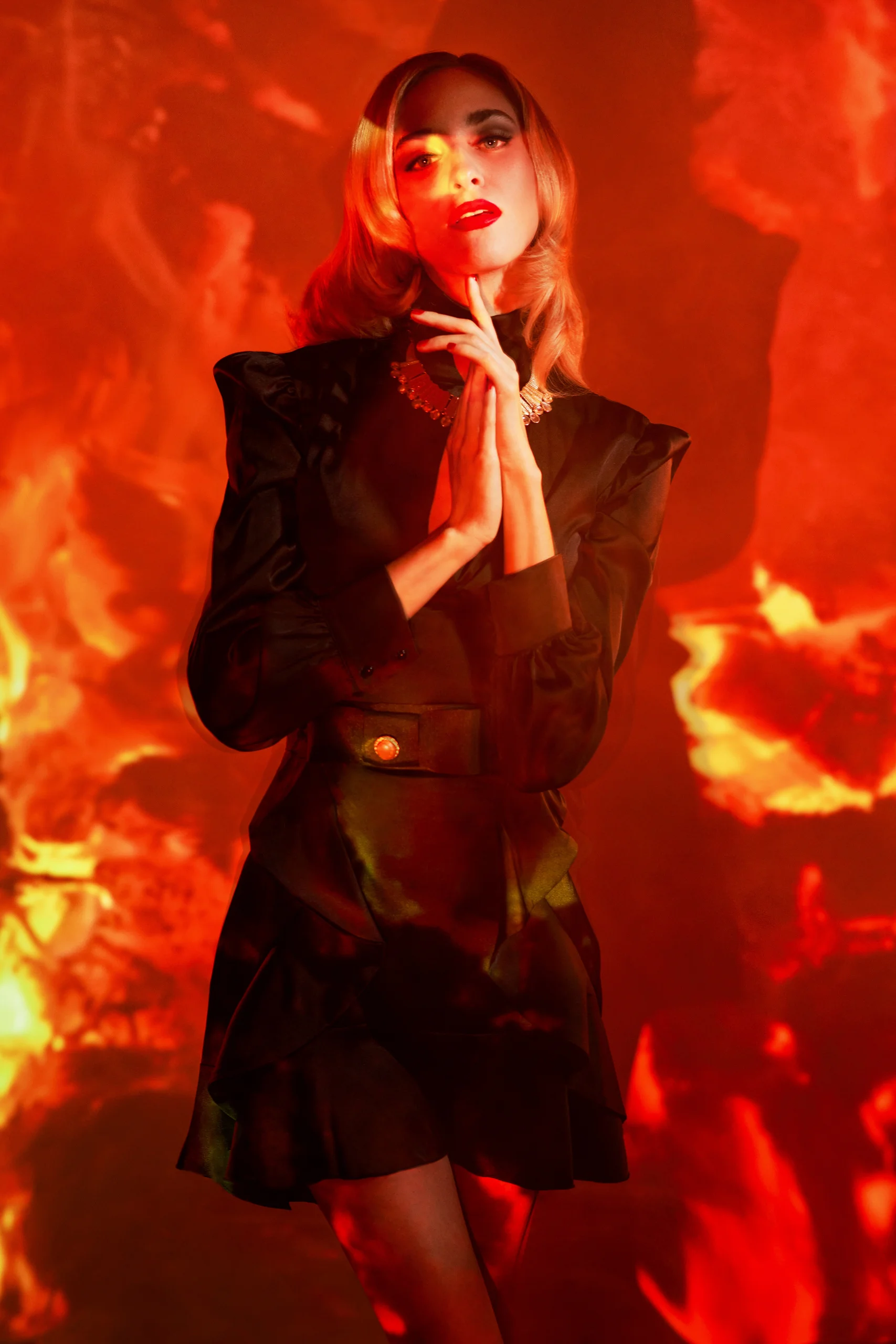 A standing model in a black outfit surrounded by orange projected patterns.