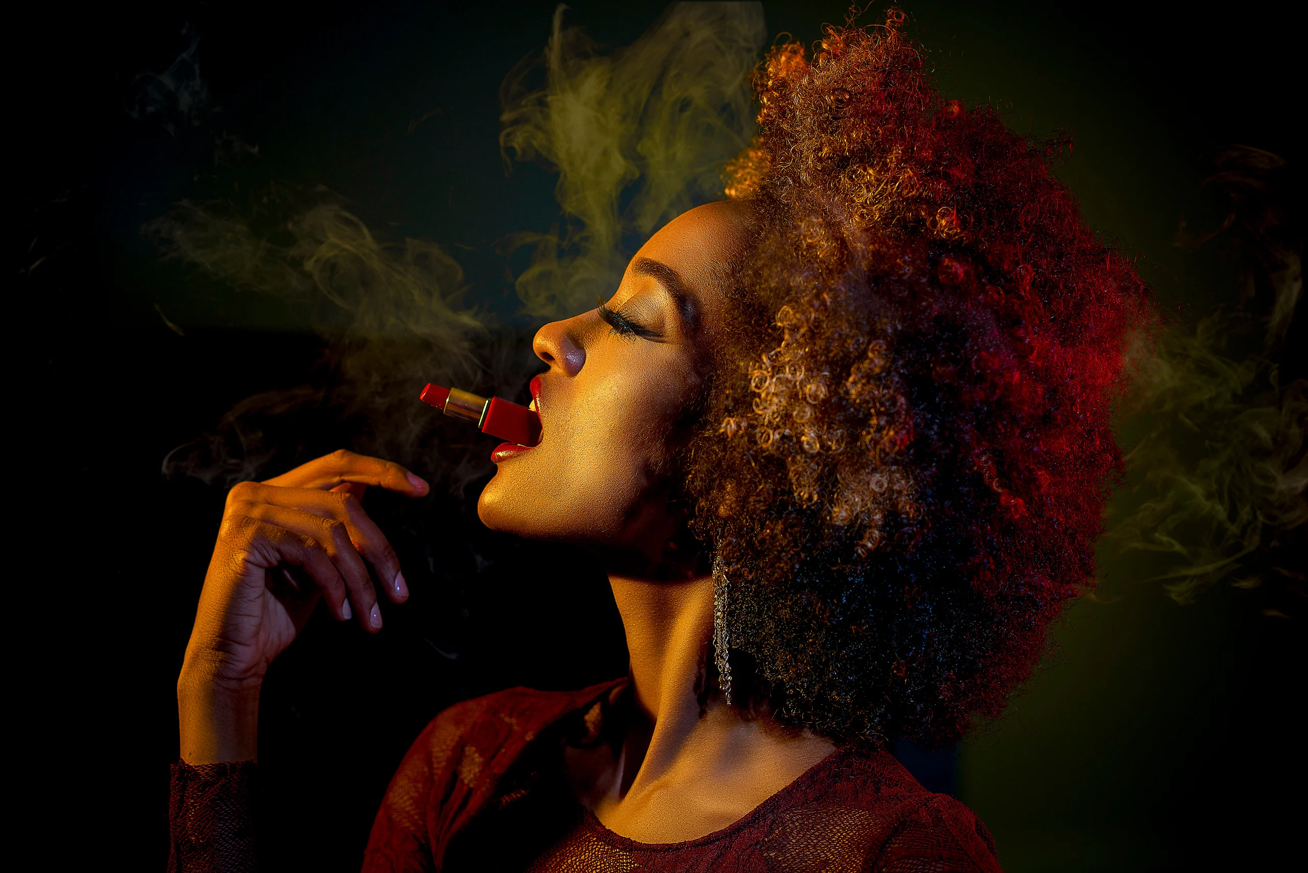 A profile portrait with curly hair, a cigar and a plume of smoke against a dark background.