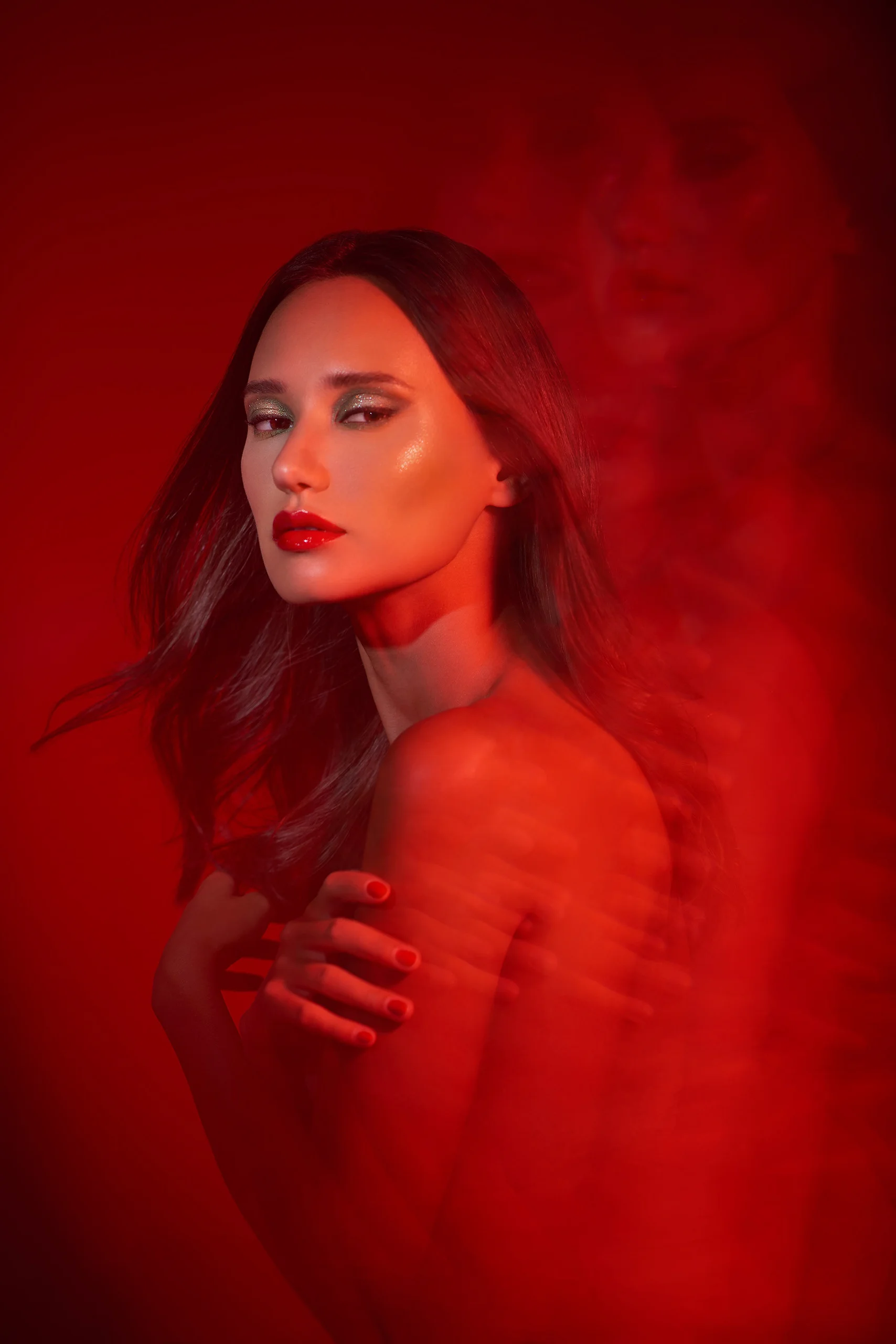 A model turns toward the camera against red light and haze.