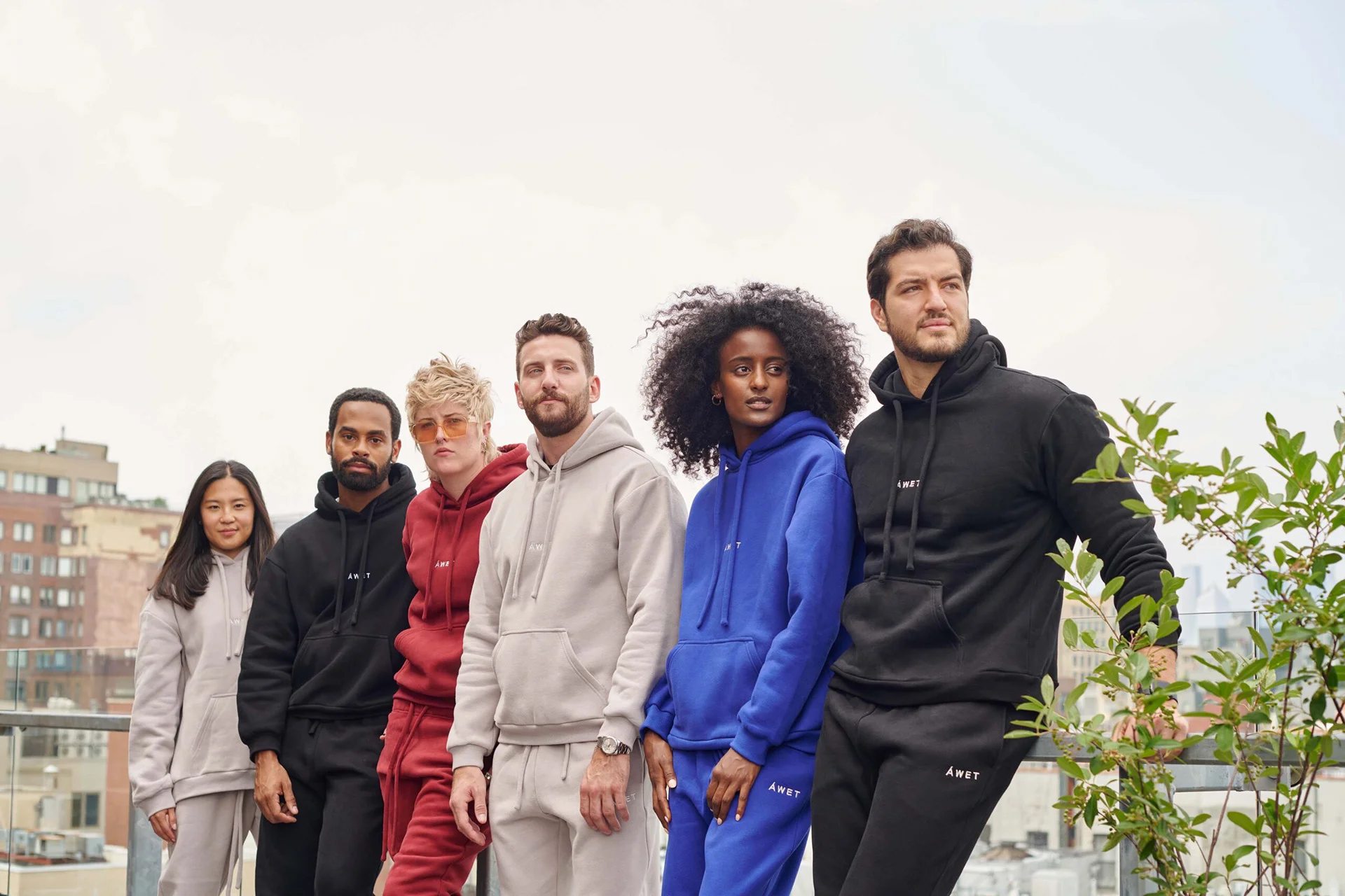 A group in ÁWET sweatshirts and trousers standing on a rooftop.