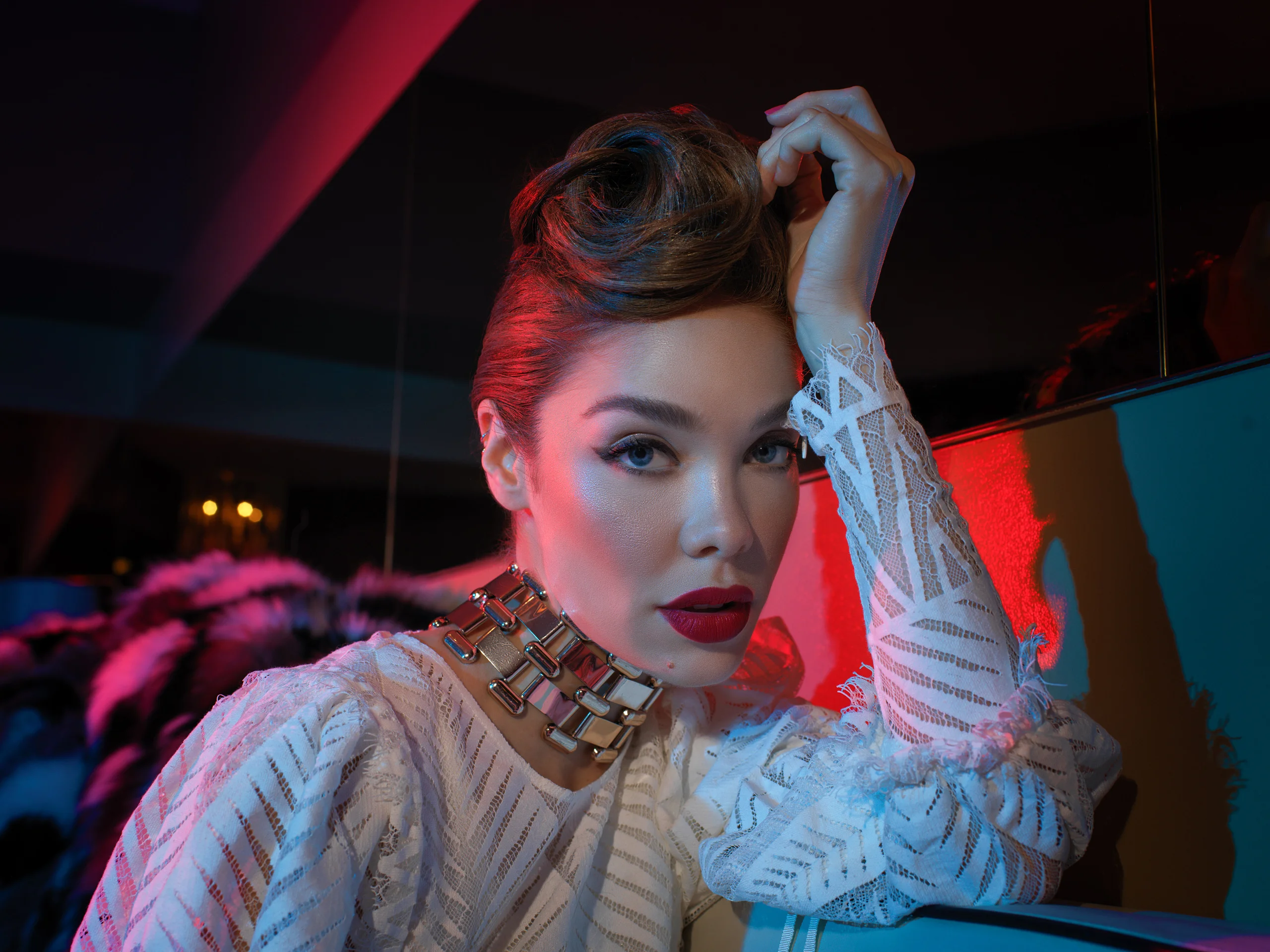 A close fashion portrait with a sculpted hairstyle, lace sleeve, and red and blue light.